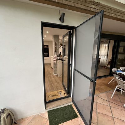 Puerta mosquitera abatible abierta hacia una terraza