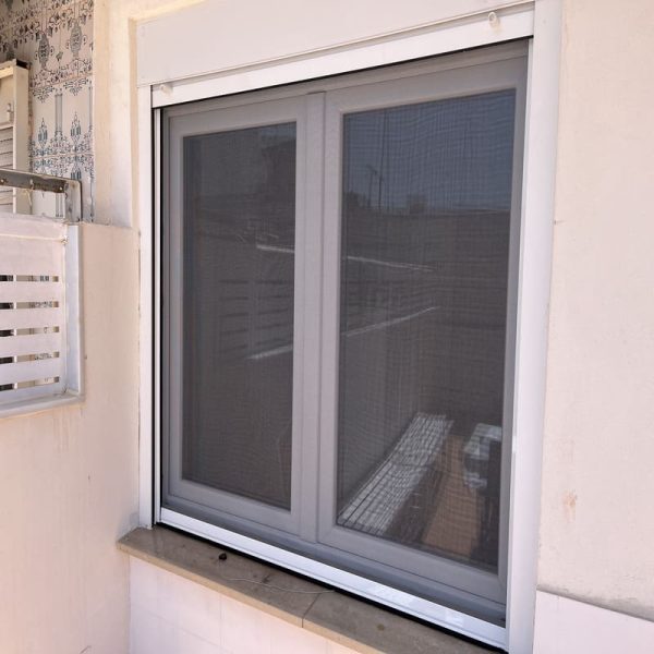Mosquitera enrollable blanca instalada en ventana en Valencia